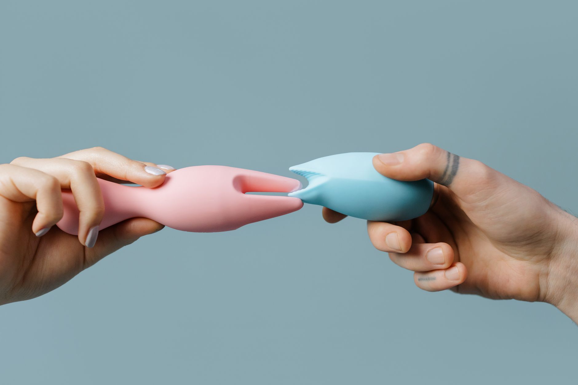 Close-up of a hand holding a pink vibrator with art books in the background