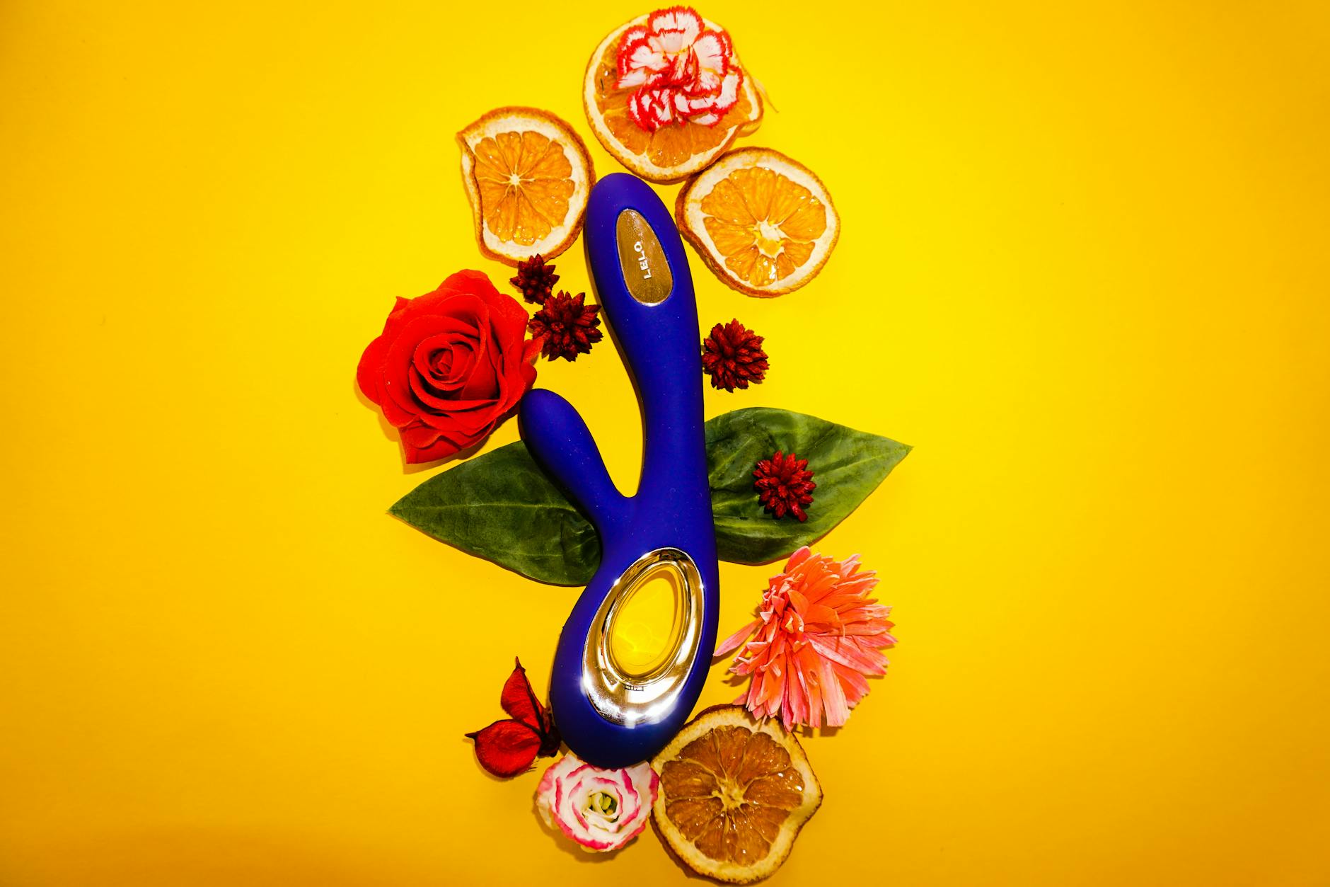 A blue silicone lemon clitoral vibrator held in hand against a solid purple background, promoting self-love and sensation reclamation
